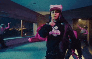 a woman wearing a black sweatshirt with a pink flower on it is dancing