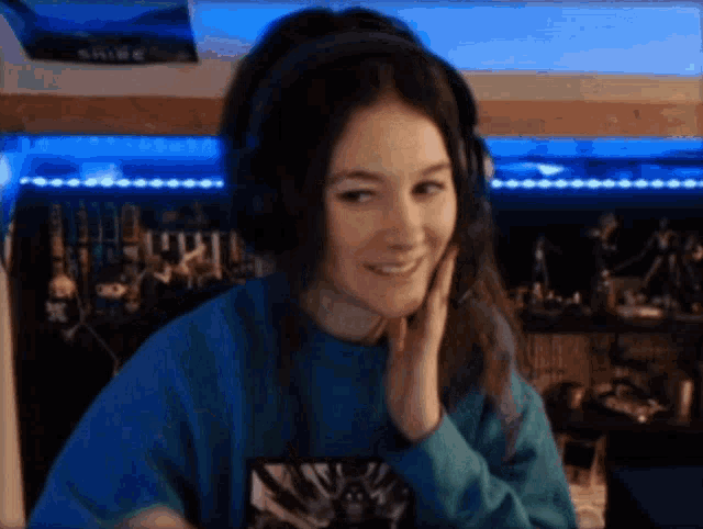 a woman wearing headphones and a blue shirt is smiling and looking at the camera