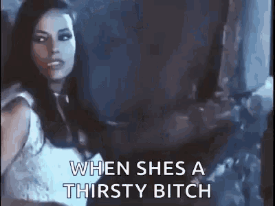 a woman in a white dress is standing in a dark room and says `` when she 's a thirsty bitch ''