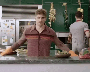 a man in a striped shirt is standing in front of a counter in a kitchen