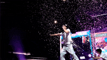 a man singing into a microphone on a stage with confetti falling