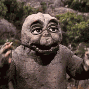 a statue of a dinosaur is standing in the woods with its arms outstretched and smiling .