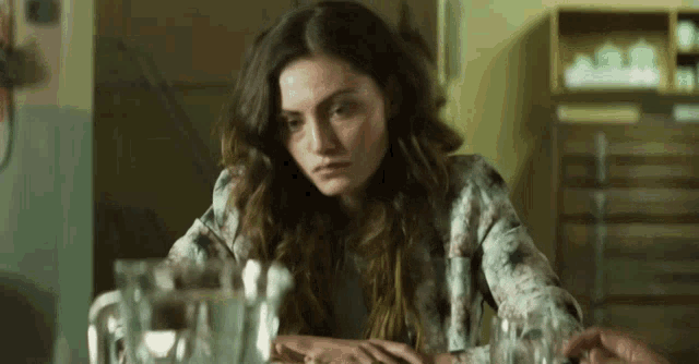a woman sits at a table with glasses of water