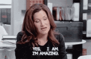 a woman is sitting at a table with her eyes closed and saying yes , i am i 'm amazing .
