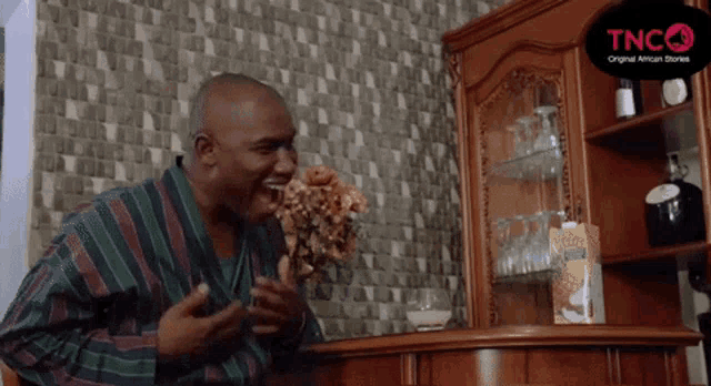 a man sitting in front of a cabinet that says tncq original african tv