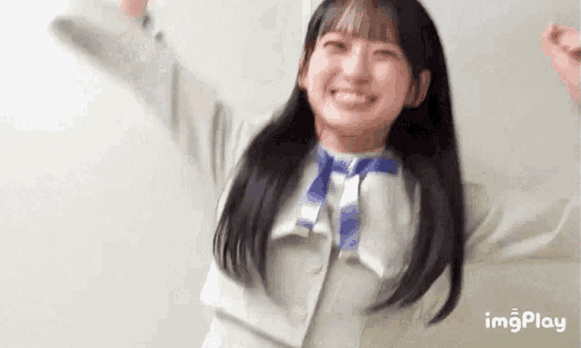 a young girl is smiling with her arms outstretched and wearing a white jacket .