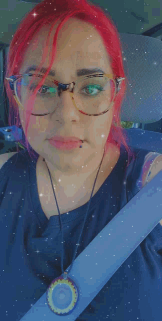 a woman with red hair is wearing glasses and a blue seat belt