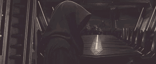 a black and white photo of a man in a hooded jacket standing in a room .