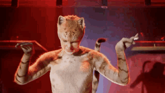 a woman dressed as a cat is dancing in a red room