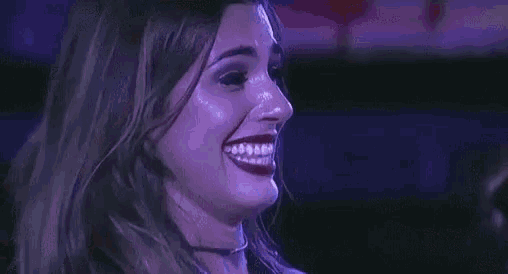 a close up of a woman 's face with a purple background and a smile .