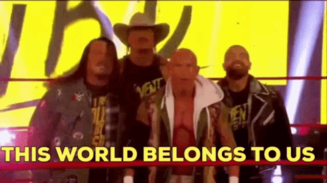 a group of wrestlers are standing in a ring with the words `` this world belongs to us '' .