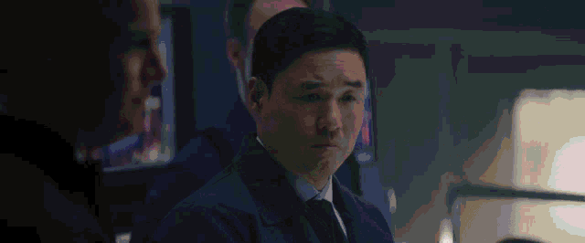 a man in a suit and tie stands in front of a sign that says " it 's a reversal of i "