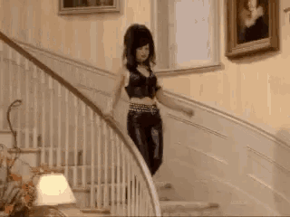 a woman is walking down a set of stairs wearing black leather pants .