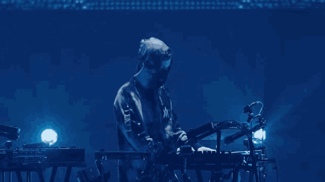 a man in a mask is playing a keyboard on a stage
