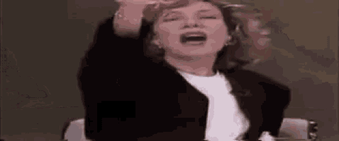 a woman is sitting in a chair with her arms in the air and her mouth open .
