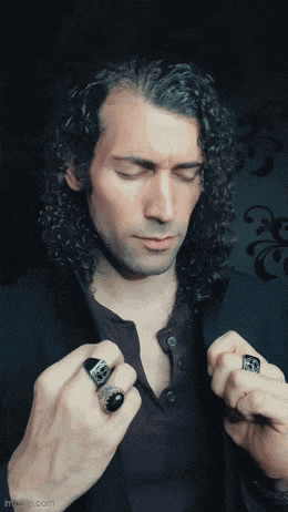 a man with long curly hair is wearing a black shirt and a black jacket