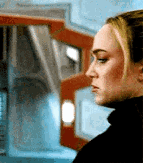a close up of a woman 's face in a room with a red door in the background .