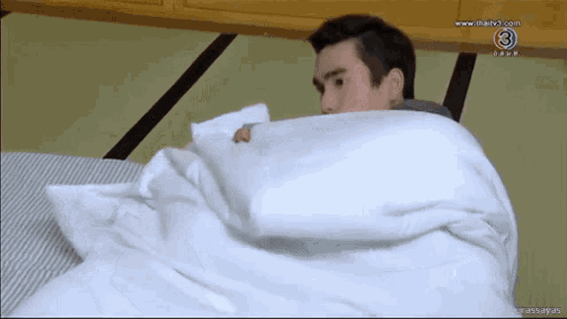 a man laying on a bed with a white blanket and the number 3 on the bottom left