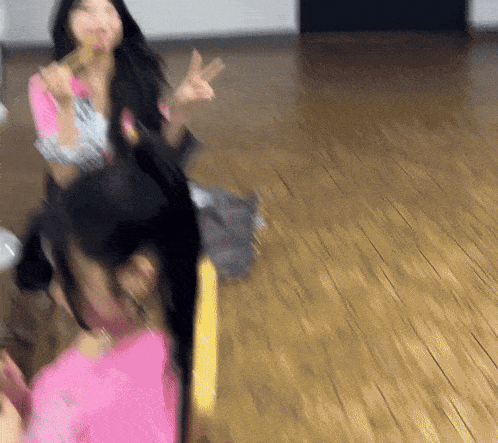a woman in a pink shirt is sitting on a wooden floor