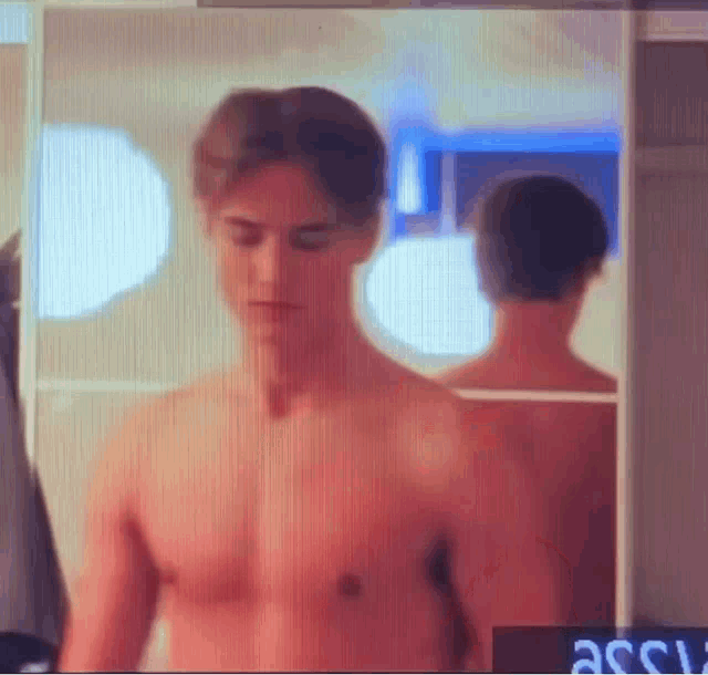 a shirtless man is standing in front of a mirror in a bathroom .