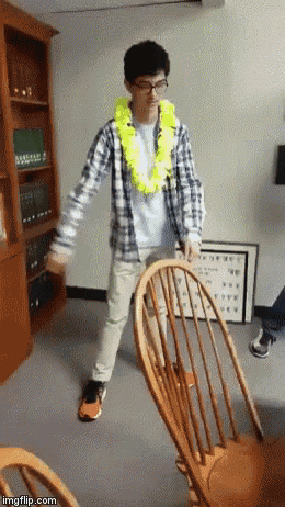 a man in a plaid shirt is standing next to a wooden rocking chair