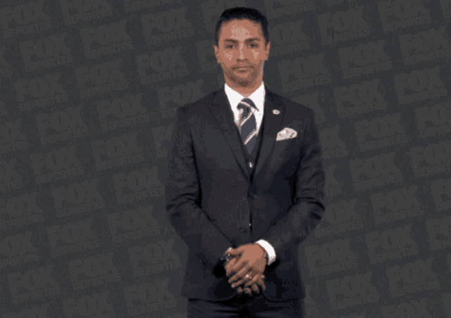 a man in a suit and tie stands in front of a fox advertisement