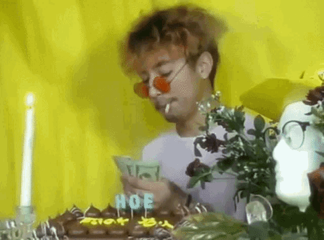 a man is smoking a cigarette in front of a birthday cake with candles that say hoe
