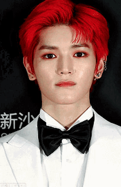 a man with red hair wearing a white suit and black bow tie