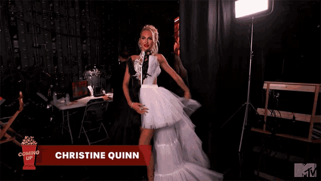 a woman is standing in front of a sign that says christine quinn on it