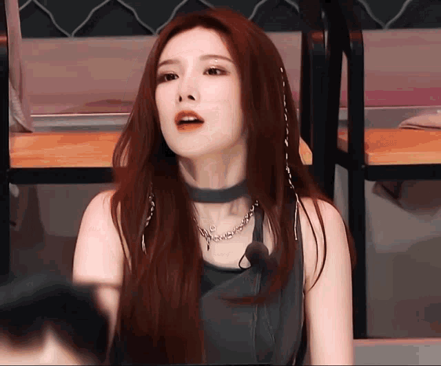 a woman with long red hair is wearing a choker and necklace