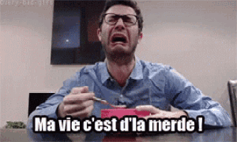 a man is sitting at a table with a bowl of food and crying while holding a spoon .