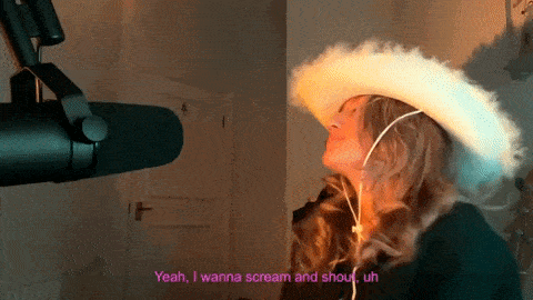 a woman wearing a cowboy hat is screaming into a microphone