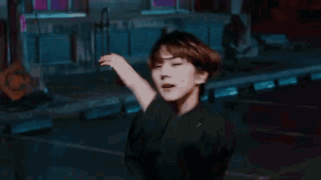 a young man in a black turtleneck is standing in a parking lot at night .