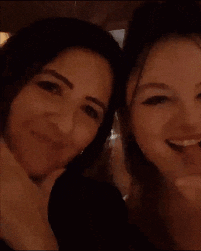 a woman is smiling in a dark room with a bar in the background