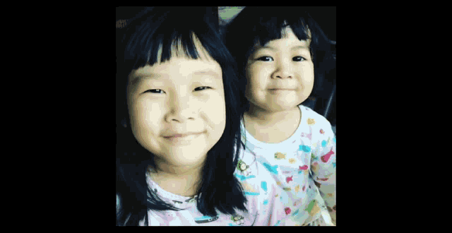 two little girls are making funny faces while wearing pajamas with boats on them