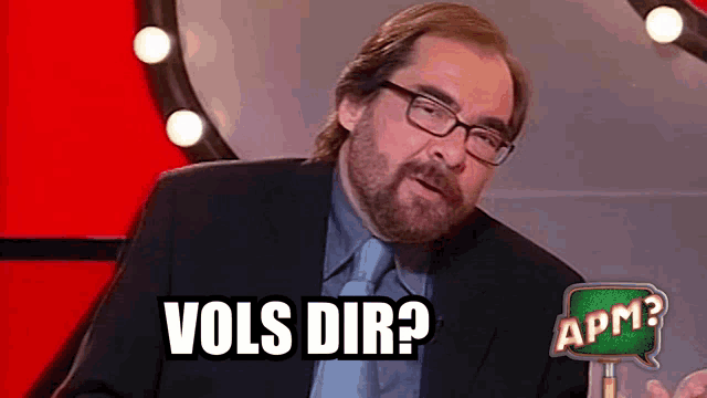 a man with glasses and a beard is asking " vols dir "