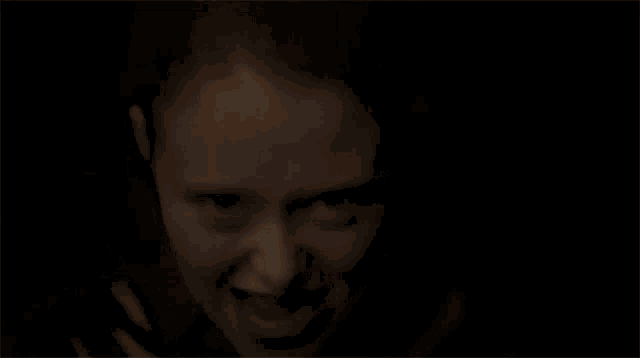 a woman with red hair is smiling and making a funny face in a dark room .