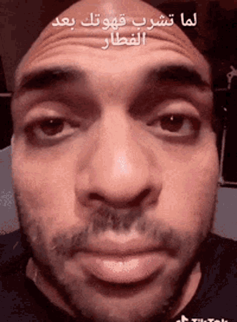 a close up of a man 's face with arabic writing on the bottom