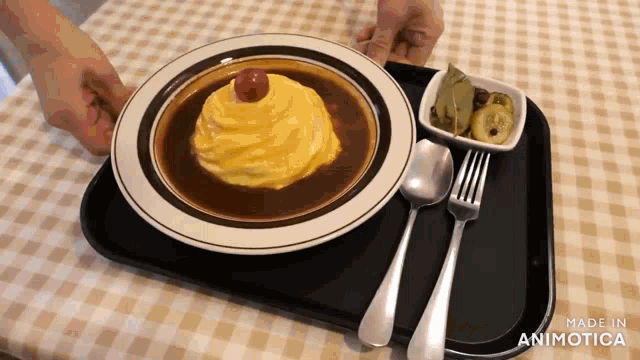 a plate of food with a fork and spoon on a tray that says made in animatica