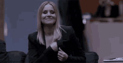a woman in a black suit is smiling while sitting at a table