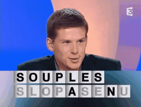 a man in a suit is sitting in front of a screen that says souples slopasenu