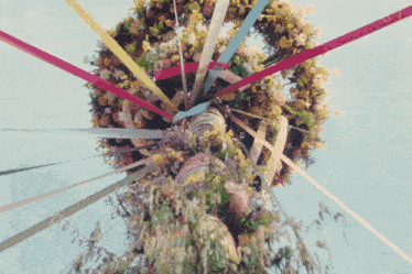 a wreath of flowers and ribbons on a pole with a blue sky in the background
