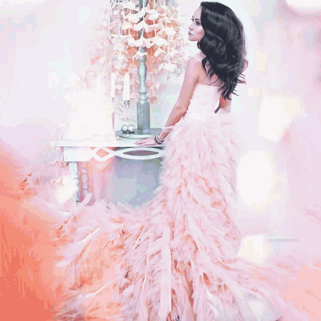 a woman in a white dress is standing next to a table with candles on it