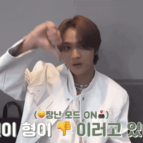 a young man in a white jacket giving a thumbs down