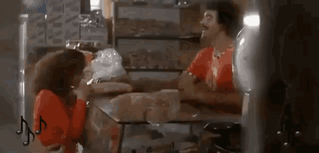a man and woman are sitting at a table in a bakery talking to each other .
