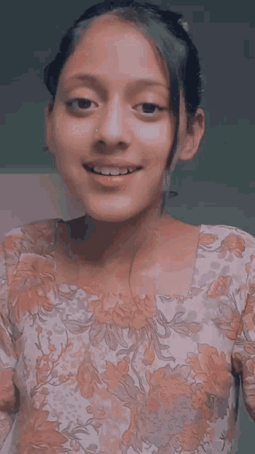 a young girl wearing a floral top is smiling for the camera