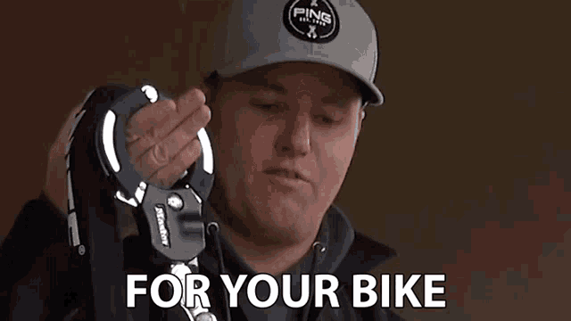 a man wearing a ping hat is holding a master lock