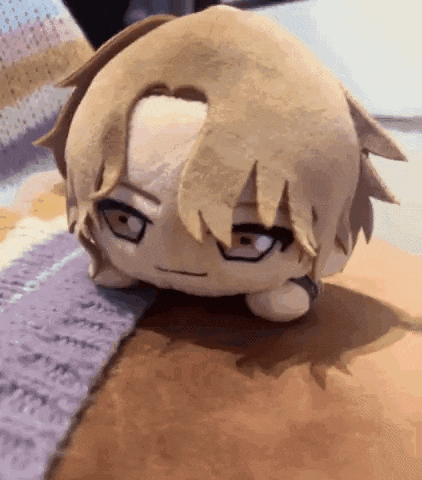 a stuffed animal is laying on a table with a purple blanket .