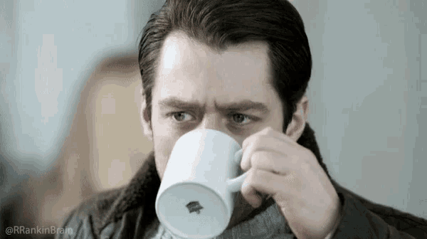a man is drinking a cup of coffee from a white cup with a logo on it .