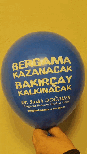 a person is holding a blue balloon that says " bergama kazanacak bakircay kalkinacak "